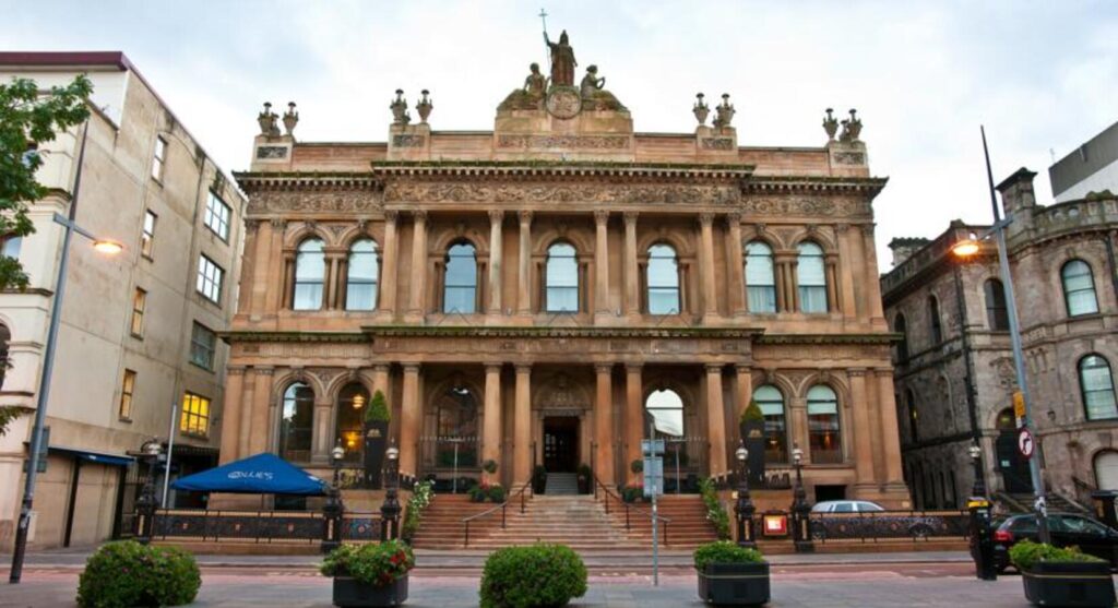 "The Merchant Hotel in Belfast, featuring it's Victorian architecture with tall arched windows, carved stonework and an elegant entrance framed by columns".
